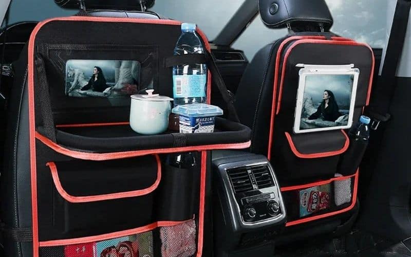 Photo de l'intérieur d'une voiture à l'arrière avec un organisateur de voiture de siège, avec rangements, tablette pour poser des choses, support pour tablette numérique etc.